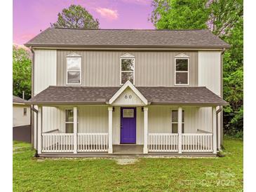 Charming two-story home featuring a covered front porch, white railings, and a vibrant purple front door at 60 Valley Nw St, Concord, NC 28025