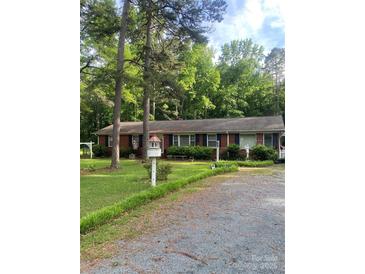 Charming one-story brick home with mature trees and a well-maintained front yard and driveway at 8524 Anette Ave, Mint Hill, NC 28227