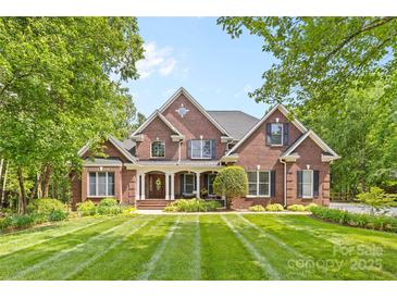 Stunning brick home featuring a meticulously manicured lawn with striped design and mature trees at 9918 Windrow Dr, Indian Trail, NC 28079