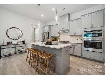 Bright kitchen features a large island, modern appliances, pendant lighting and grey cabinets at 3125 Beacon Heights Rd, Indian Land, SC 29707