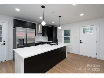 Modern kitchen featuring black cabinets, stainless steel appliances, and a large island with a white countertop at 4500 Ridgeley Dr, Charlotte, NC 28208