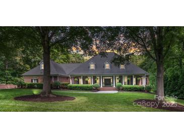 Charming brick home with manicured lawn, mature trees, and inviting front porch with classic columns at 4920 Parview S Dr, Charlotte, NC 28226