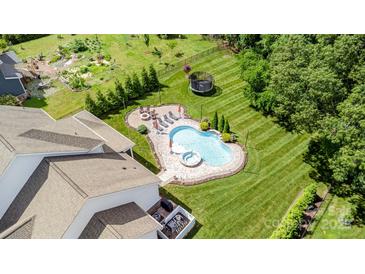 An inviting pool area features a stone patio, manicured lawn, fire pit, and multiple lounge chairs at 112 S Shore Dr, Belmont, NC 28012