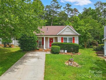 Charming one-story home featuring red accents, manicured lawn and mature trees at 1006 Washburn Ct, Monroe, NC 28110
