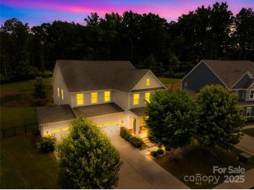 Stunning two-story home with a three-car garage and manicured lawn, brightly lit at dusk at 10901 Greenvale Dr, Harrisburg, NC 28075