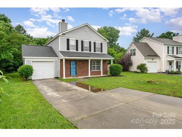 Charming two-story home with a brick facade, gray siding, lush green lawn, and private driveway at 2903 Rockingham Sw Ct, Concord, NC 28025