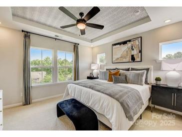 A bright main bedroom features large windows, tray ceiling and ensuite bathroom at 316 Catawba Ave, Davidson, NC 28036