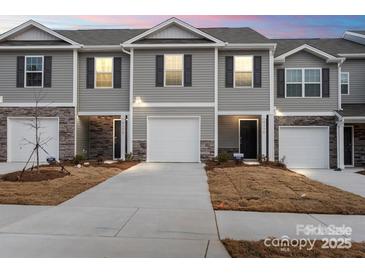 New townhome showing garage, stone accents, neutral paint, and a manicured lawn at 4116 Lurelin Ln, Charlotte, NC 28262