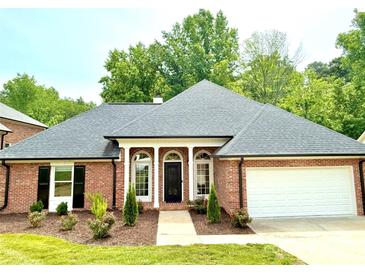 Charming brick home featuring a well-manicured lawn, complemented by a two car garage and a stylish, columned entryway at 456 Brook Valley Ne Ct, Concord, NC 28025