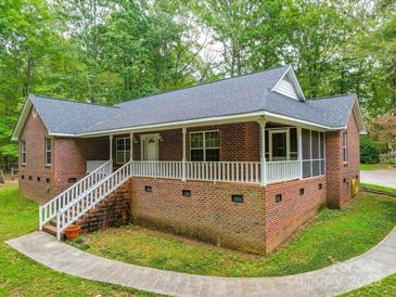 Charming brick home featuring a large front porch with white railings, surrounded by mature trees and landscaping at 4620 Binwhe Ln, Gastonia, NC 28052