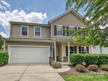 Tan two-story home with a two-car garage, and well-maintained landscaping at 9027 Gray Willow Rd, Charlotte, NC 28227