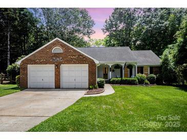 Charming brick home featuring a well-manicured lawn, attached garage, and cozy front porch at 1014 Covewood Ct, Charlotte, NC 28270