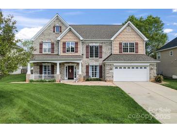 Charming two-story brick home featuring a welcoming front porch and well-manicured lawn at 1016 Spanish Moss Rd, Indian Trail, NC 28079