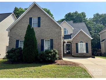 Charming two-story brick home with manicured lawn, black shutters, and a basketball hoop over the driveway at 1043 Cambrook Ct, Concord, NC 28027