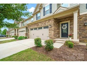 Charming townhome featuring stone accents, two-car garage, and an inviting front entrance with well-manicured landscaping at 117 Lanyard Dr # E, Mooresville, NC 28117