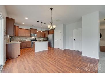 Open kitchen boasts stainless steel appliances, granite countertops, and stylish lighting fixtures at 1412 Afternoon Sun Rd, Matthews, NC 28104