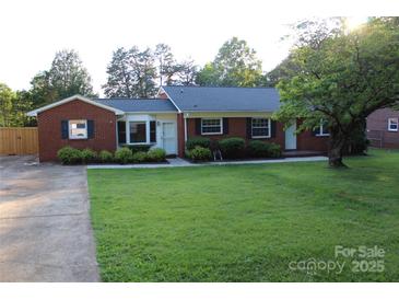 Charming brick home featuring a well-maintained lawn and mature trees, creating a welcoming curb appeal at 1421 Thompson Ave, Charlotte, NC 28216