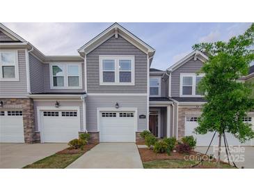 Charming townhome featuring a gray exterior, attached garage, and manicured landscaping at 14806 Tamarack Dr, Charlotte, NC 28278