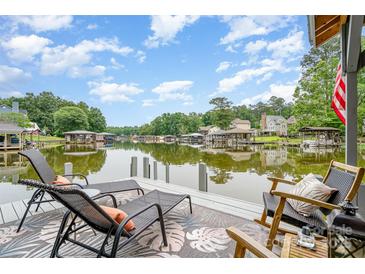 A waterfront view from a private dock, featuring comfortable lounge chairs and scenic lake views under a partly cloudy blue sky at 307 Lake Head Rd, Norwood, NC 28128