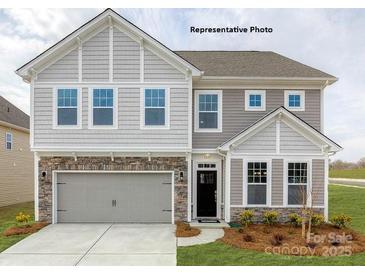 Charming two-story home with stone accents, gray siding, and a welcoming front entrance at 115 Asmodean Ln, Troutman, NC 28166