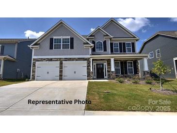 Charming two-story home with a well-manicured lawn, a two car garage and stone and gray toned siding at 127 Asmodean Ln, Troutman, NC 28166