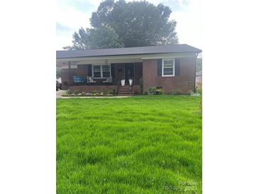 Charming brick home featuring a covered front porch, complemented by a lush green lawn at 202 Kenwood Ave, Cherryville, NC 28021