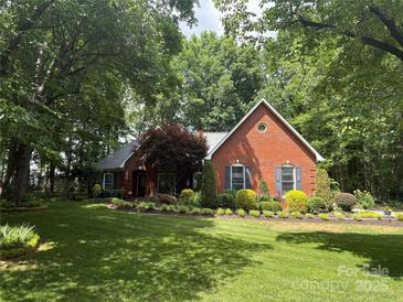 Charming red brick home featuring a well-manicured lawn, mature trees, and colorful landscaping at 5208 Black Oak Ln, Waxhaw, NC 28173