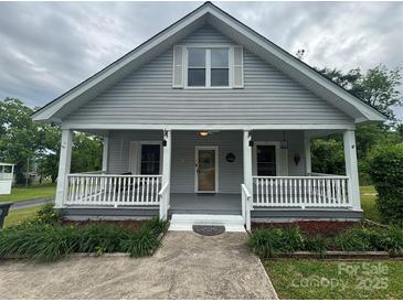 Charming gray home featuring a cozy front porch with white railings and a well-manicured lawn at 103 Duke St, Great Falls, SC 29055