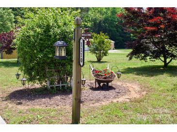 Inviting front yard featuring a charming address post and a wheelbarrow overflowing with vibrant flowers at 1110 Archer Farm Dr, Salisbury, NC 28144