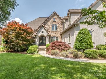 Inviting stone-accented home with lush landscaping and a curved walkway leading to the elegant arched front door at 1404 Lookout Cir, Waxhaw, NC 28173