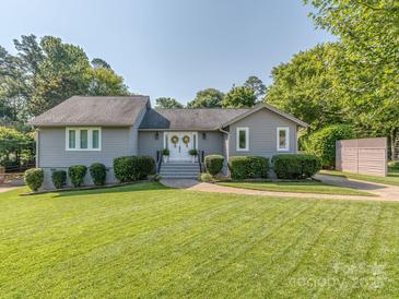 Charming single-story home with manicured lawn, complemented by lush greenery, and a welcoming entrance at 214 Wilcrest Dr, Matthews, NC 28105