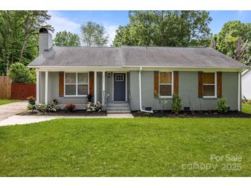 Charming one-story home with a beautifully landscaped front yard and gray brick exterior at 6406 Old Meadow Rd, Charlotte, NC 28227