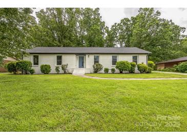 Charming brick home with a blue front door, well-manicured lawn, and mature landscaping at 6641 Pawnee Dr, Charlotte, NC 28214
