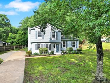 Charming two-story home with light blue siding, dark shutters, green lawn, and mature trees at 8514 Timber Crest Cir, Charlotte, NC 28226
