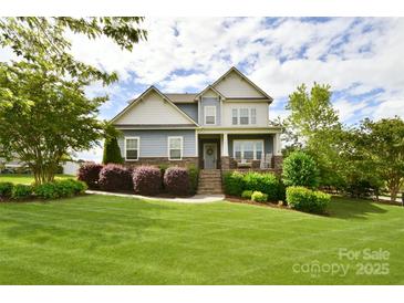 Charming two-story home boasts lush landscaping and a welcoming front porch with rocking chairs at 104 Rockridge Point Dr, Mooresville, NC 28117