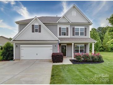 Charming two-story home with gray siding, shutters, landscaped yard, a two-car garage, and covered front porch at 114 Sierra Chase Dr, Statesville, NC 28677