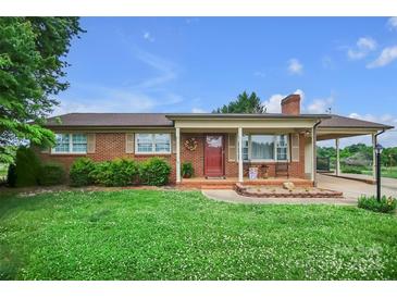 Charming brick home featuring a cozy front porch and a well-manicured lawn with mature landscaping at 1609 Troy Rd, Shelby, NC 28150