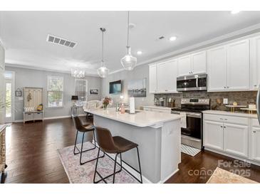 Bright kitchen features white cabinetry, stainless appliances, island with pendant lighting, and adjacent living space at 344 Linestowe Dr, Belmont, NC 28012