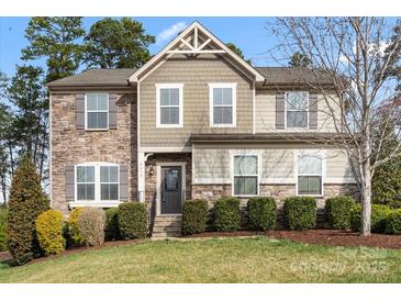 Charming two-story home with stone accents, well-manicured lawn, and lush landscaping at 4095 Harmattan Dr, Denver, NC 28037