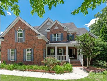 Charming brick two-story home with well-maintained landscaping and a welcoming front porch at 8914 Landsdowne Ave, Harrisburg, NC 28075