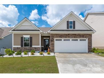 Charming home featuring manicured landscaping, a stone facade, and a two-car garage on a sunny day at 9034 Evercrisp Ln, Charlotte, NC 28215
