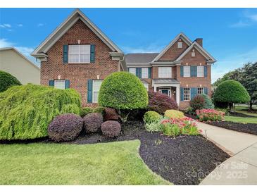 Beautiful brick home with manicured lawn, colorful landscaping, and classic blue shutters at 1000 Sarandon Dr, Matthews, NC 28104