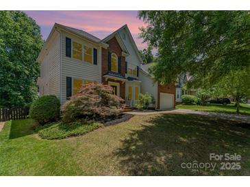 Charming two-story home features a blend of brick and siding, complemented by well-manicured landscaping and mature trees at 1147 Anduin Falls Dr, Charlotte, NC 28269