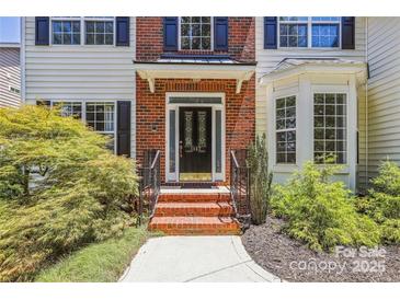Inviting front entrance features a black door, brick steps, and lush landscaping at 1147 Anduin Falls Dr, Charlotte, NC 28269