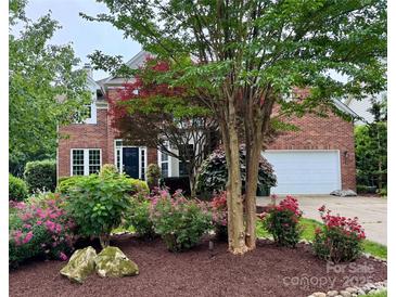 Beautiful brick home with meticulously landscaped front yard featuring vibrant flowers and mature trees at 15826 Hollingbourne Rd, Huntersville, NC 28078