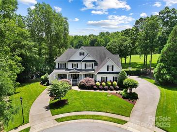 Stately two-story home with meticulously landscaped front yard, circular driveway, and lush surrounding trees at 19946 River Falls Dr, Davidson, NC 28036