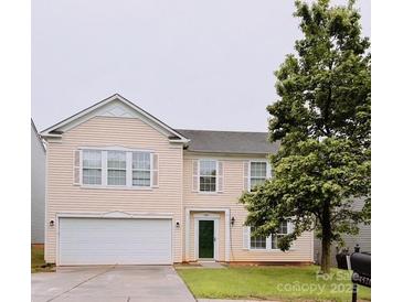 Two-story home with light yellow siding, white trim, attached garage, and mature landscaping at 4521 Palustris Ct, Charlotte, NC 28269