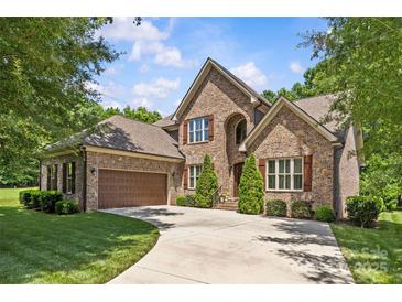 Elegant brick home featuring a spacious three-car garage and lush, green landscaping, with manicured lawn at 6211 Cruden Bay Way, Charlotte, NC 28277