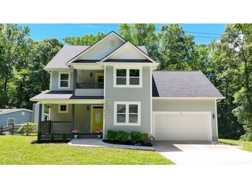 Charming two-story home with a well-manicured lawn, beautiful plants, gray siding, and a welcoming yellow front door at 8701 W Dixie Dr, Charlotte, NC 28278