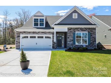 Charming home featuring a stone facade, dormer window, well-manicured lawn, and a two-car garage at Lot 29 Bozeman Ct # 29, Stanley, NC 28164